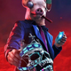 A Watch Dogs Legion character wearing a pig mask holds up a crystal skull while surrounded by red smoke.